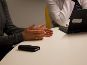 Visual interpretation: Two women in discussion, only hands and table visual.